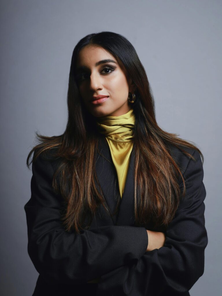 Confident woman with long hair poses gracefully in a studio setting, exuding elegance.
